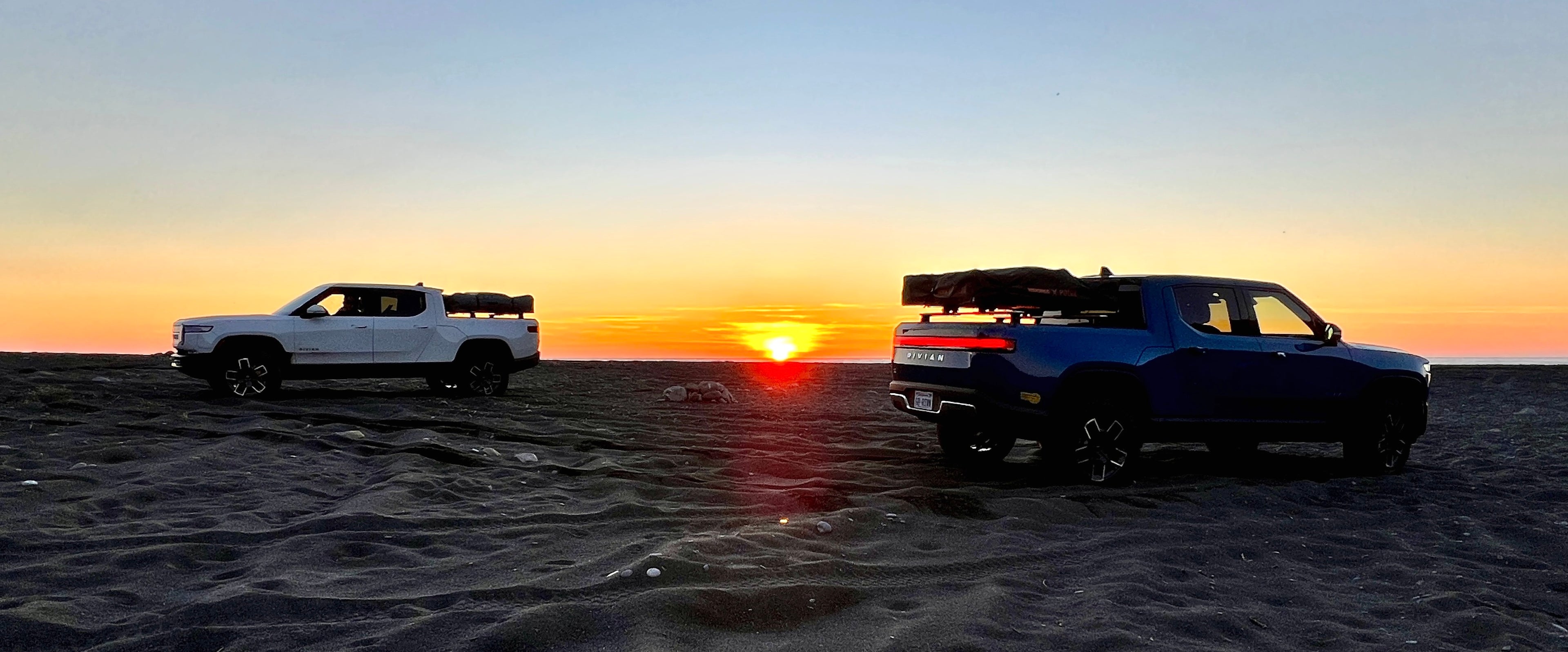 Two Rivian R1Ts on the beach